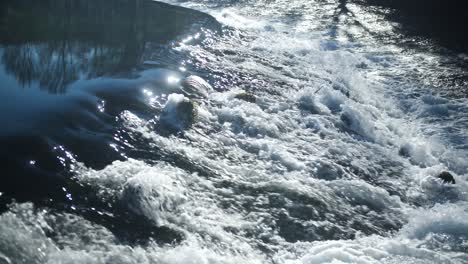 Rushing-river-waters-with-reflective-surface-under-daylight,-dynamic-and-powerful-nature-scene