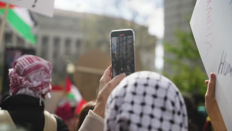 Una-Mujer-Con-Una-Keffiyah-Filma-A-Una-Multitud-De-Manifestantes-En-Una-Marcha-A-Favor-De-Palestina.