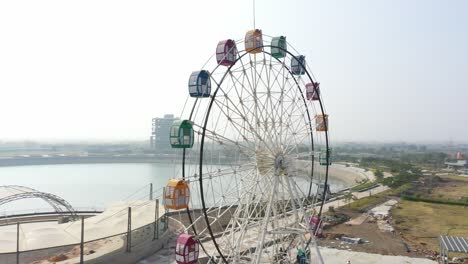 Rajkot-Atal-See:-Die-Drohnenansicht-Der-Telefonkamera-Bewegt-Sich-Zur-Seite,-Es-Gibt-Ein-Großes-Riesenrad-Und-An-Der-Seite-Sind-Viele-Gärten-Sichtbar,-Rajkots-Neue-Rennstrecke,-Atal-Sarovar