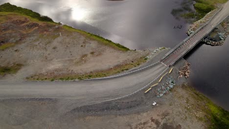 Spiral-aerial-perspective-of-a-small-metal-bridge-over-a-quiet-river-in-Cucao,-Chiloe-Chile