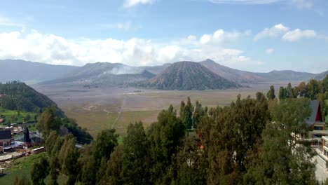 Fangen-Sie-Die-Ruhige-Schönheit-Des-Dorflebens-Am-Fuße-Des-Mount-Bromo-Ein,-Während-Der-Majestätische-Berg-Eine-Atemberaubende-Kulisse-Bietet,-4K-Luftaufnahmen-Mit-Einer-Drohne