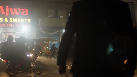 Silhouetten-Von-Menschen,-Die-Nachts-In-Einer-Belebten-Straße-In-Gujarat,-Pakistan,-Spazieren-Gehen,-Straßenszene