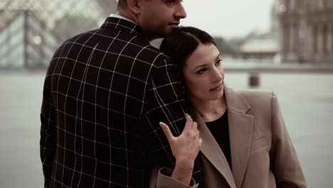 Indian-elegant-couple-in-suits-showing-traditionald-hand-painting-cuddling-in-an-artistic-dreamy-thoughtfull-pose-enjoying-the-moment-without-tourists-at-the-Museum-du-Louvre-Pyramids-in-Paris-France