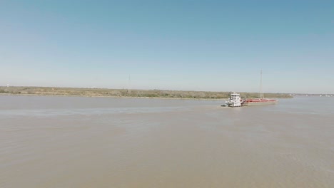 Una-Vista-Aérea-De-Un-Remolcador-Maniobrando-Una-Barcaza-A-Lo-Largo-Del-Canal-De-Navegación-De-Houston-En-Un-Día-Soleado-En-Houston,-Texas.