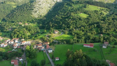 Vuelo-De-Drones-Con-Cámara-Gira-De-Derecha-A-Izquierda-En-Un-Pequeño-Y-Estrecho-Valle-En-Un-Pueblo-Con-Sus-Prados-Para-Cultivos-Y-Ganado-Con-Pasto-Verde-Con-Sus-Bosques-De-Robles-En-Cantabria-españa