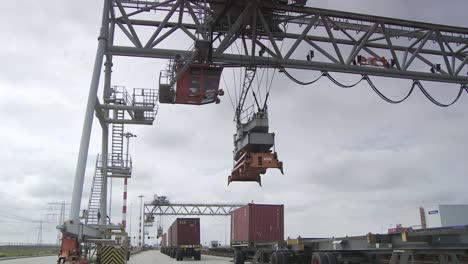 Puerto-Industrial-Con-Grúa-De-Contenedores-Cargando-Carga-En-Un-Día-Nublado,-Trabajadores-Supervisando-La-Operación,-Toma-Estática