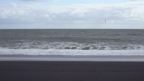 Wellen-Brechen-Sich-Am-Schwarzen-Sandstrand-Islands-Unter-Einem-Bewölkten-Himmel