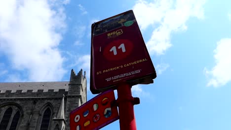 Big-Bus-red-stop-indicating-many-languages-at-St-Patrick's-Cathedral,-Dublin