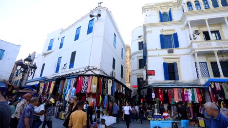 Bustling-market-scene-in-Tunis-with-vibrant-stalls-and-local-crowd,-under-clear-blue-sky