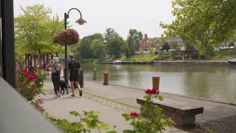 Couple-With-Dog-Talking-While-Walking-On-Erie-Canal-Towpath-At-Pittsford,-New-York,-USA