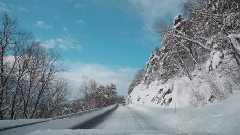 POV-Video-Einer-Fahrt-Bei-Tageslicht-Durch-Die-Verschneiten-Straßen-Der-Westlichen-Fjorde-Norwegens,-Umgeben-Von-Hohen,-Schneebedeckten-Bergen-Mit-Bäumen