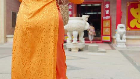 Close-up-of-an-Asian-girl-in-national-costume-with-clogs,-walking-and-praying-at-a-pagoda