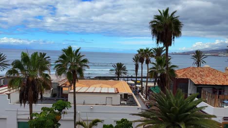 Balcony-view-of-Tenerife-rocky-coast,-tropical-palm-tree-beach-huts