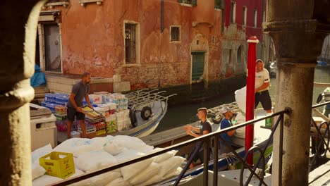 Logística-En-Venecia:-El-Hombre-Arroja-Mercancías-De-Un-Barco-A-Otro-Para-Entregar-Cajas-Y-Comida-A-Tiendas-Y-Personas-Que-Viven-En-La-Ciudad-Histórica