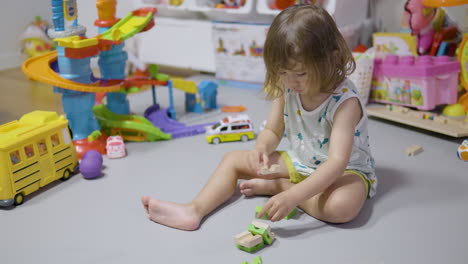 Blond-Toddler-Girl-Building-Blocks-Tower-At-Home-Living-Room-Sitting-on-Grey-Mat---slow-motion