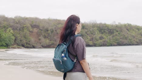 Frau-Mit-Rucksack-Blickt-Auf-Den-Ruhigen-Segresse-Strand-In-Grenada,-Bewölkter-Tag,-Ruhige-Szene