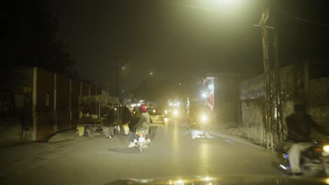 Bustling-night-market-street-scene-in-Gujrat,-Pakistan-with-vibrant-lights-and-traffic