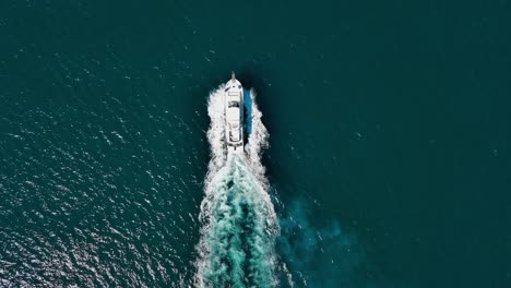 Vista-Aérea-De-La-Lancha-Moviéndose-A-Alta-Velocidad-Mientras-Deja-Un-Rastro-Blanco-En-La-Superficie-Del-Mar-Azul.