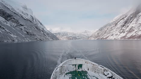 POV-video-of-a-ferry-ride-through-Geirangerfjord-in-winter,-featuring-stunning-views-of-snow-covered-mountains,-a-bright-sky,-and-reflections-in-the-fjord