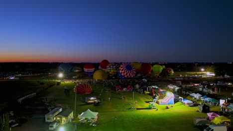 Aerial-View-of-a-Line-of-Performing-Hot-Air-Balloons-Glow-on-a-Summer-Evening