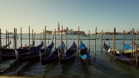 Gondolas,-typical-boats-from-Venice,-moving-on-the-water-in-the-lagoon-near-the-main-square