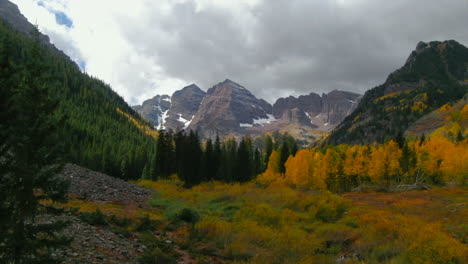 Maroon-Bells-Pyramid-Peak-Aspen-Snowmass-Colorado-wilderness-Incredible-stunning-cinematic-aerial-drone-fall-autumn-colors-snow-covered-Rocky-Mountains-peaks-sunny-cloudy-morning-upward-jib-motion