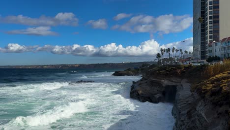 Springflut-In-Der-Bucht-Von-La-Jolla,-Blick-Auf-Die-Skyline-über-Wellen,-Die-Gegen-Die-Klippen-Brechen,-Vorbeifliegende-Vögel.