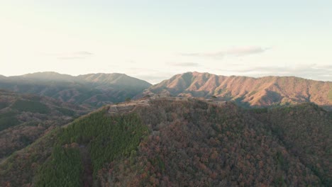 Aerial-Drone-Fly-Above-Japanese-Castle-Ruins-Landscape,-Mountain-Range-Skyline