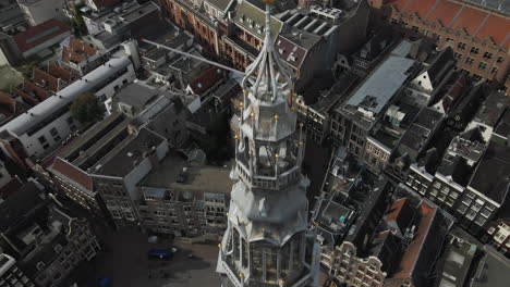 Aerial-view-of-the-bell-tower-of-the-Old-Church-with-a-clock-with-buildings-and-apartments-at-background-during-daytime-in-Amsterdam,-The-Netherlands