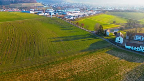 Luftaufnahme-Von-üppigem-Ackerland-Neben-Einem-Industriepark-Bei-Sonnenuntergang