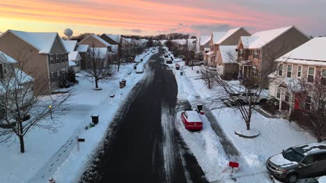 Sunset-sky-above-a-snowy-street-with-lined-duplex-houses-and-parked-vehicles