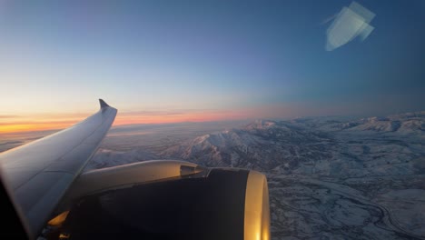 Sunset-flight-over-rugged-mountain-terrain---view-from-a-commercial-jet-window-at-sunset