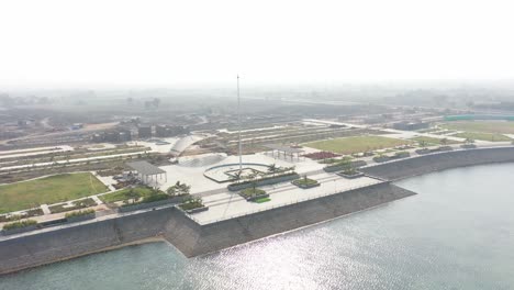Rajkot-Atal-lake-drone-view-drone-camera-is-moving-towards-the-side-till-the-water-is-falling-and-the-water-is-shining-in-the-water,-Rajkot-New-Race-Course,-Atal-Sarovar