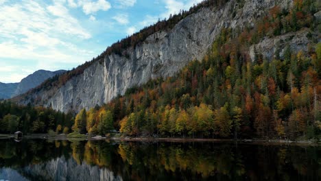 Tranquil-lake-reflects-vibrant-autumn-foliage,-sunlight-filters-through-trees,-creating-a-mesmerizing-kaleidoscope-of-color