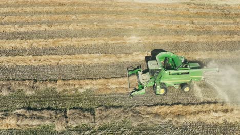 Tracking-high-level-drone-shot-of-a-John-Deere-combine-picking-up-a-canola-swath