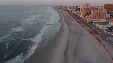 Drone-Volando-Hacia-Atrás-Mostrando-La-Playa-A-Lo-Largo-De-La-Costa-Atlántica-De-La-Ciudad-Al-Amanecer