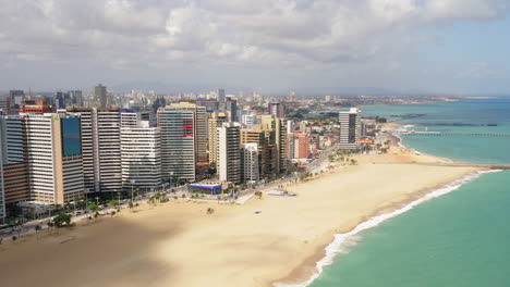 Aerial-view-of-the-buldings-in-front-of-the-sea,-the-empty-beach-in-a-cloudy-day,-Fortaleza,-Ceara,-Brazil