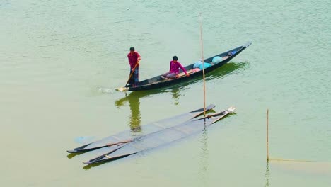 Dos-Hombres-Montando-Un-Barco-De-Madera-Tradicional-En-El-Río-De-Bangladesh
