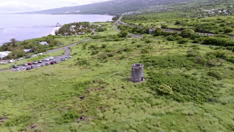 Drone-view-orbiting-right-around-the-lime-kiln,-revealing-the-parking-area-of-Pointe-au-Sel-in-Saint-Leu,-Reunion-Island