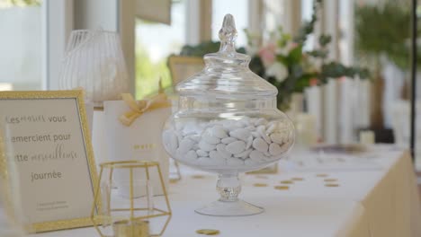 Elegant-jars-brimming-with-delicate-white-dragées,-grace-the-tables-at-wedding