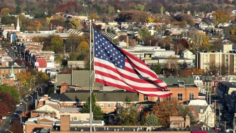 American-flag-waving-over-urban-cityscape-with-autumn-foliage