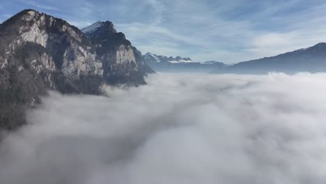 Majestic-Cliffs-Amidst-Walensee-Fog,-Switzerland-aerial-above-clouds