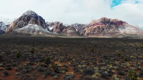 Aerial-drone-shot-of-snowcapped-mountains-with-a-cloudy-sky-in-the-daytime