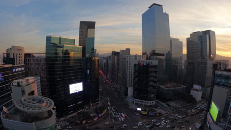 Sonnenuntergang,-Skyline-Des-Bezirks-Gangnam-Bei-Sonnenuntergang,-Zeitraffer-über-Den-Wolkenkratzern-Im-Stadtzentrum-Von-Seoul-Und-Dem-Autoverkehr-In-Der-Dämmerung-–-Blick-Von-Oben-Vom-Dach