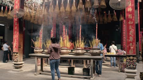 People-praying-with-incense-at-Jade-Emperor-Pagoda,-Saigon,-midday,-spiritual-atmosphere,-handheld-shot