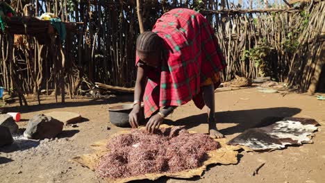 Tribal-African-woman-in-traditional-clothing-prepares-food-on-the-ground-of-her-remote-village