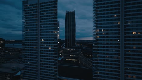 Vista-Aérea-Por-Drones-Del-Moderno-Edificio-De-Oficinas-Y-Apartamentos-Al-Atardecer-O-Por-La-Noche