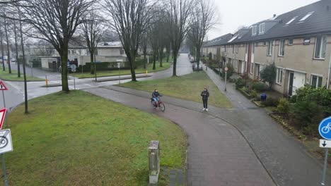 Luftaufnahme-Eines-Radfahrers,-Der-An-Einem-Regnerischen-Tag-In-Den-Niederlanden-Durch-Ein-Vorstadtviertel-Radelt