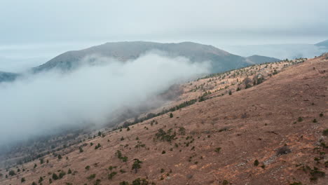 Neblige-Berge-Mit-Niedrigen-Wolken-Und-Spärlicher-Vegetation,-Die-Eine-Ruhige-Landschaft-Schaffen