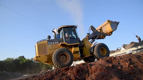 Niedrige-Winkelansicht-Eines-Radladers-Auf-Einer-Baustelle-An-Einem-Sonnigen-Tag,-Schmutz-Im-Vordergrund